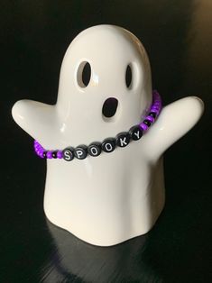 a white ghost with purple beads on it's neck and the word scary spelled in black letters