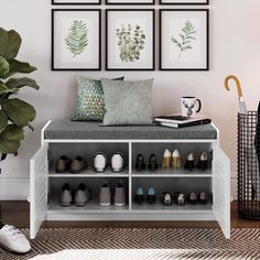 a white bench with shoes on it in front of four framed pictures and a potted plant