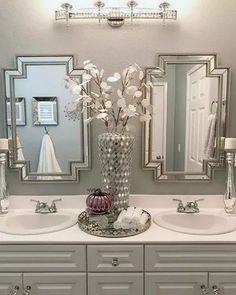 a bathroom with two sinks, mirrors and flowers in a vase on the counter top