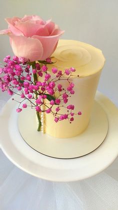 a white plate topped with a cake covered in frosting and pink flowers on top of it