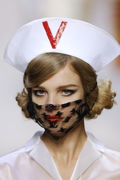 a woman wearing a white sailor's hat with black lace on her face and nose