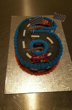 a birthday cake that is shaped to look like a race track with cars on it