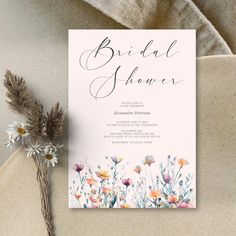 a white and pink floral bridal shower card on top of a table next to flowers