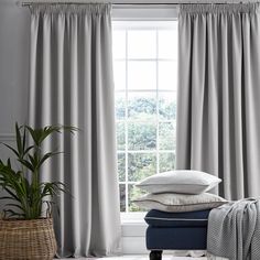 a window with curtains and pillows on it in front of a basket filled with blankets