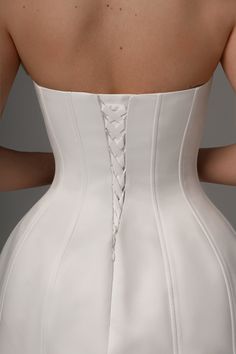 the back of a woman's white wedding dress with laces on the side