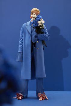 a man in blue coat and pants holding flowers