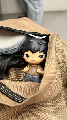 a small doll sitting in the pocket of a bag