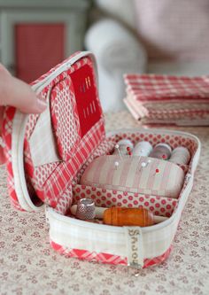 a hand is opening a red and white case on a table with other items in it