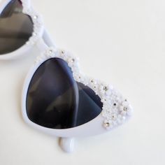 Look stunning on your wedding day in these amazing floral heart shaped sunglasses. These glasses are perfect for the person that loves white, rhinestones and pearls to wear at a garden party, bachelorette party wedding or bridal shower. These will look stunning in engagement photos or wedding photos. Not getting married? These are perfect to complete your music festival or concert look. Pair with your favorite summer dress. Each pair is hand embellished with the cutest miniature flowers and the White Heart-shaped Sunglasses For Summer, White Heart-shaped Sunglasses For Valentine's Day, Heart-shaped Sunglasses For Summer Weddings, Heart-shaped Wedding Sunglasses For Summer, Elegant Heart-shaped Sunglasses With Tinted Lenses, Elegant Heart-shaped Tinted Sunglasses, Elegant Heart-shaped Party Sunglasses, Elegant White Sunglasses For Wedding, Elegant White Wedding Sunglasses