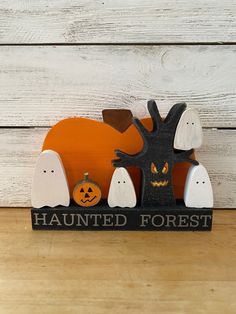 a wooden sign that says,'haunted forest'with ghost and pumpkins on it