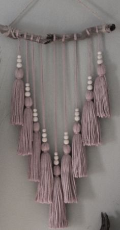 a wall hanging with tassels and white beads on it's sides in a room