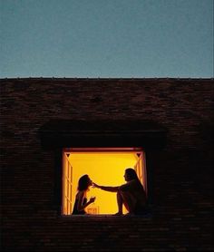 two women are sitting on the ledge of a building and one is holding her hand out to another woman