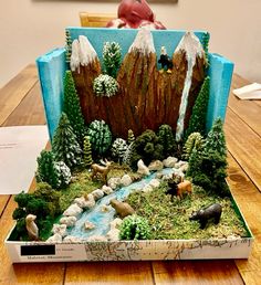 a cake that is shaped like a mountain with trees and animals in it on a table