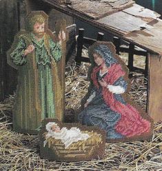 two nativity figurines sitting in hay next to a basket