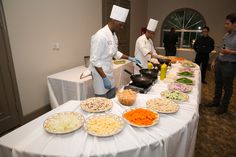 three chefs preparing food at a buffet table