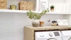 a washer and dryer in a room with white tiles on the wall behind them