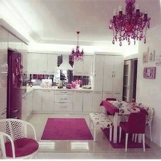 a white and pink kitchen with chandelier hanging from the ceiling, dining room table set for four