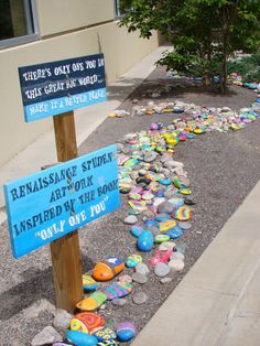 there is a sign that has been placed on the sidewalk with rocks all over it