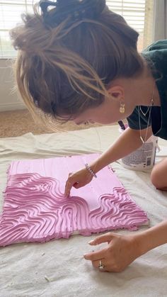 a woman is painting a piece of art on the floor