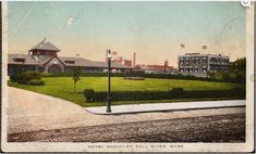 an old postcard shows the view of a city from across the street, with train tracks and buildings in the background