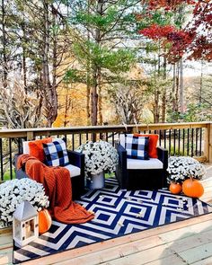 an outdoor deck decorated for fall with pumpkins, hydrangeas and plaid pillows