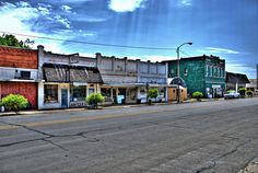 an empty street with buildings and cars parked on the side