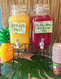 three different colored drinks are sitting on a table with pineapples and paper plates