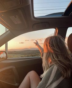 two people sitting in the back seat of a car with their hands up to the sun