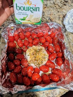 strawberries and cheese in foil sitting on a counter next to a bottle of boursin