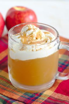 an apple cider with whipped cream and caramel on top in a glass mug