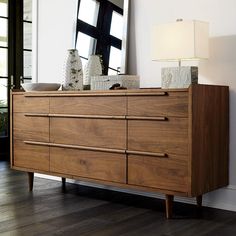 a large wooden dresser sitting next to a lamp on top of a hard wood floor