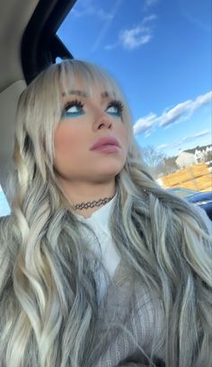 a woman with long blonde hair sitting in a car