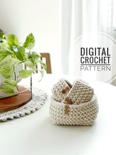 a crocheted basket sitting on top of a table next to a potted plant