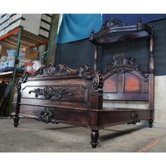 an antique wooden bed frame with intricate carvings on the headboard and foot board, in a warehouse