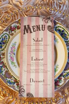 a plate with a menu on it sitting on top of a tablecloth covered in gold foil