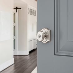 an open door with a knob on it in front of a white wall and wood floor