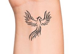 a bird tattoo on the side of a woman's leg, with black ink