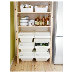 an organized pantry with white containers and drinks on the bottom shelf next to a refrigerator