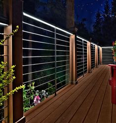 a wooden deck with lights on it and flowers in the foreground, at night