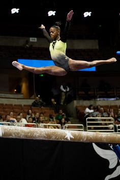 a woman is performing on the balance beam