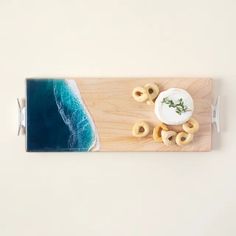 an overhead view of some food on a wooden board near the water and beach with waves