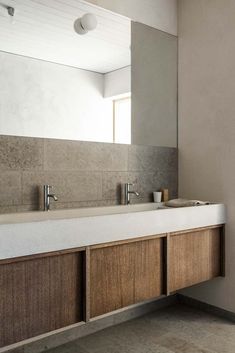 a bathroom sink sitting under a large mirror next to a wall mounted faucet