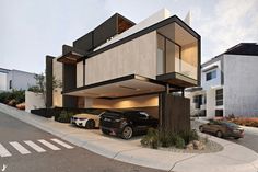 two cars are parked in front of a modern house with an open garage door and balconies on the second floor