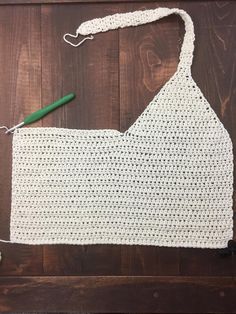 a crocheted apron is being worked on by someone using a green handled knitting needle