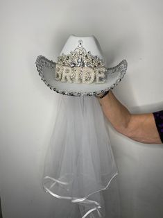 a bride's hat with the word bride written on it is held up against a wall