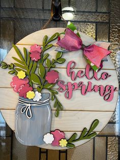 a wooden sign that says hello spring with flowers in a mason jar and pink bow