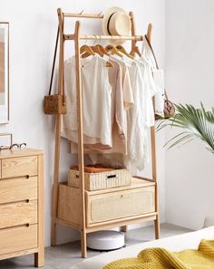 a clothes rack in a bedroom next to a dresser with baskets and shirts on it