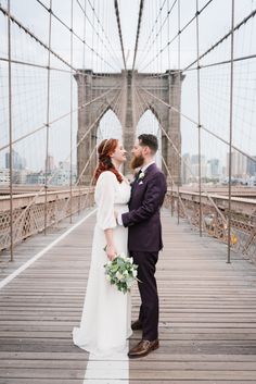 a bride and groom standing on the brooklyn bridge