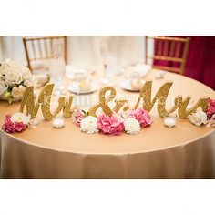 the table is decorated with flowers and mr and mrs signs on it's side