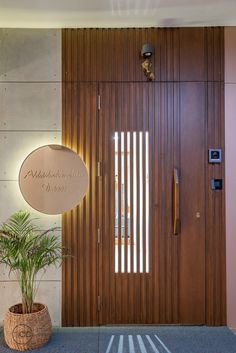 the entrance to an office building with a wooden door and plant in front of it